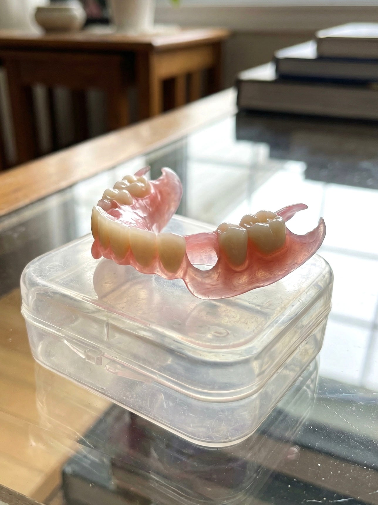 Partial dentures in a clear plastic case on a glass surface
